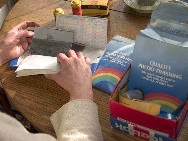 A person sorting through a shoe box of photos and negatives.